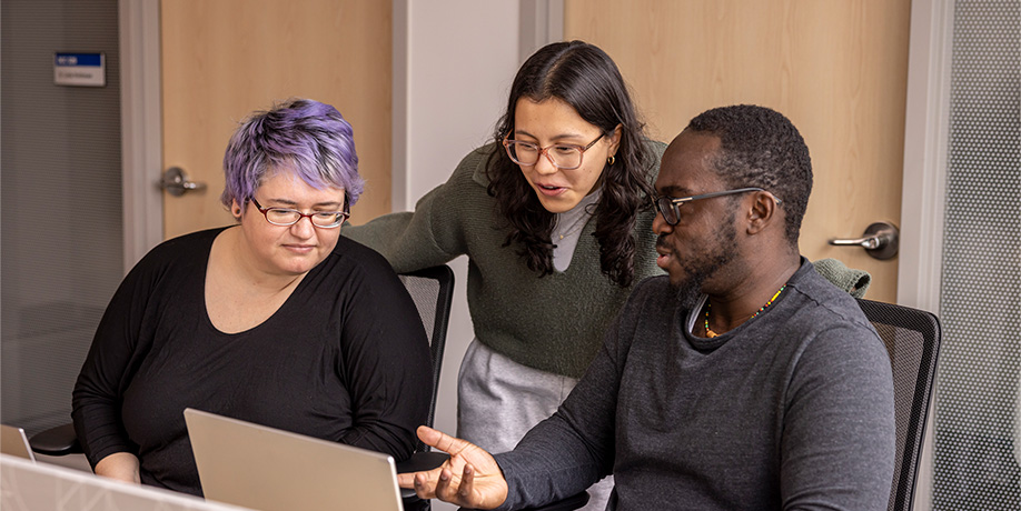 three people looking at laptop screen 