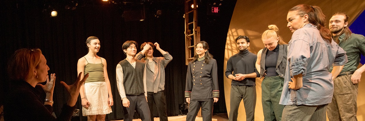 students stand onstage in costume taking notes from a director