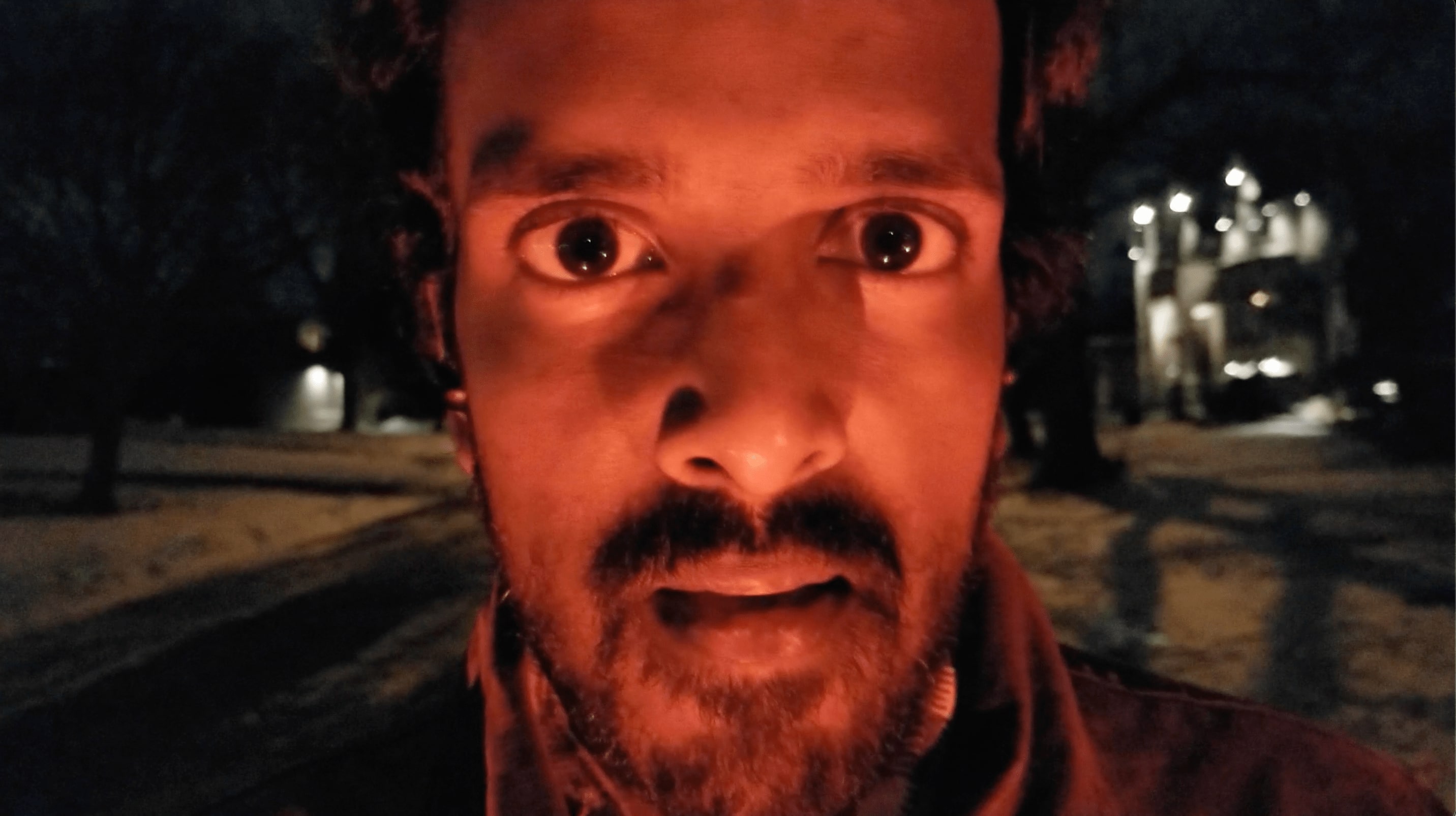 Lit with red light, an actor stares with wide eyes and a parted mouth