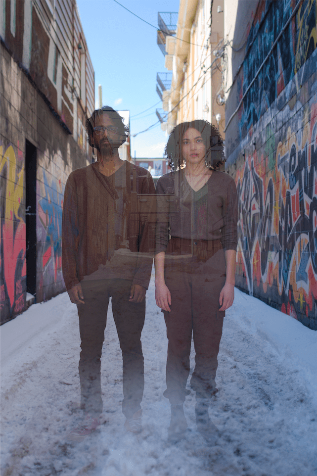 2 Ghostly figures stand side by side in a snowy alleyway.