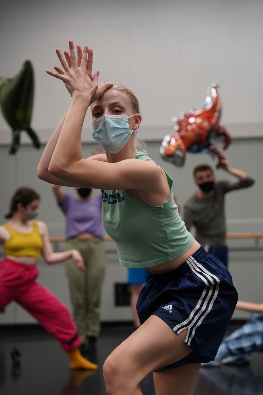 A dancer squats with their hands in a prayer pose at their forehead