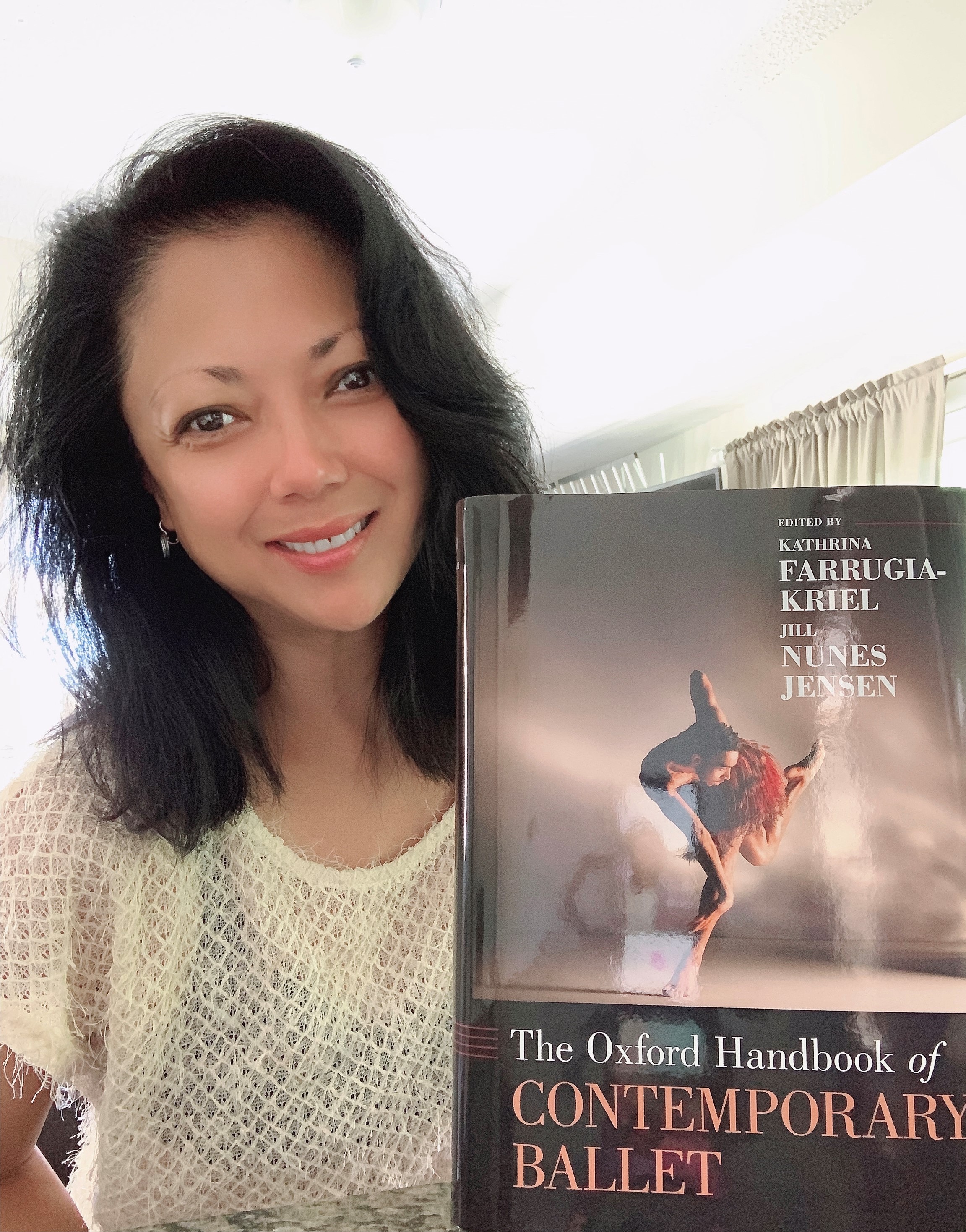 Tanya Evidente smiles and holds a book for which she wrote a chapter, The Oxford Handbook of Contemporary Ballet