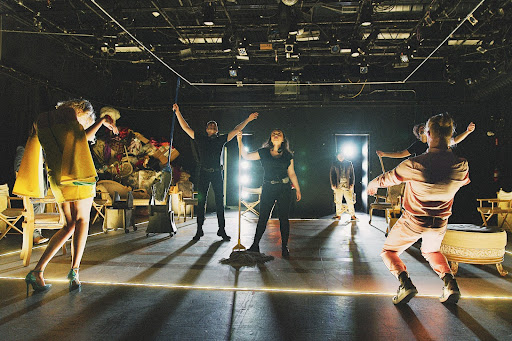 Performers moving around a dark theatre space