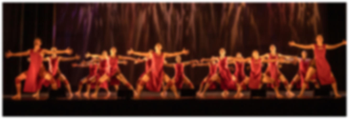 dancers onstage with their arms outstretched blurred into the background