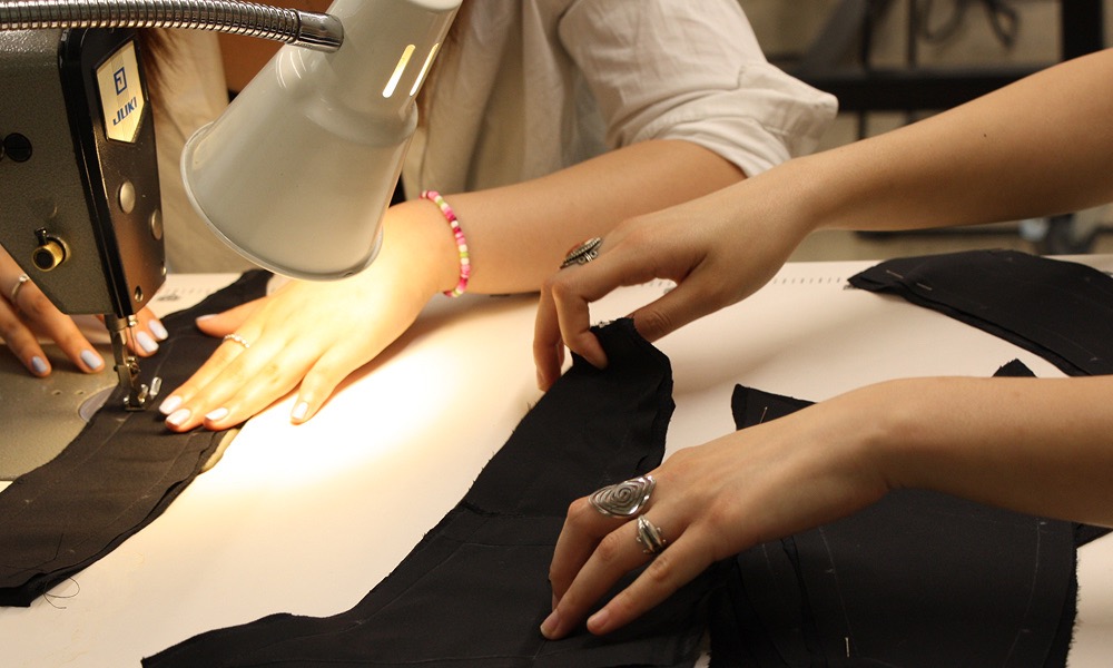 two students' hands working with a sewing machine