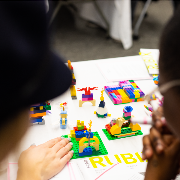 Two students discussing Lego constructions on a table