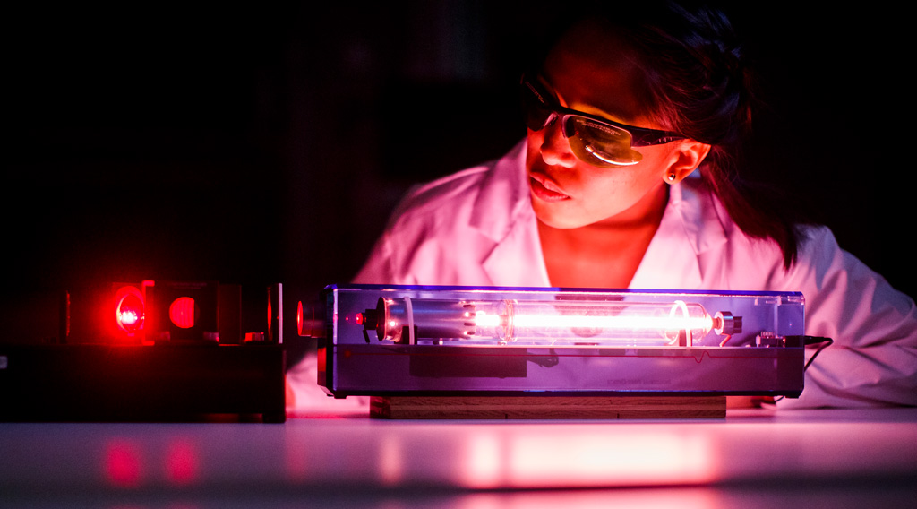 Physics undergraduate student working in lab with light laser.