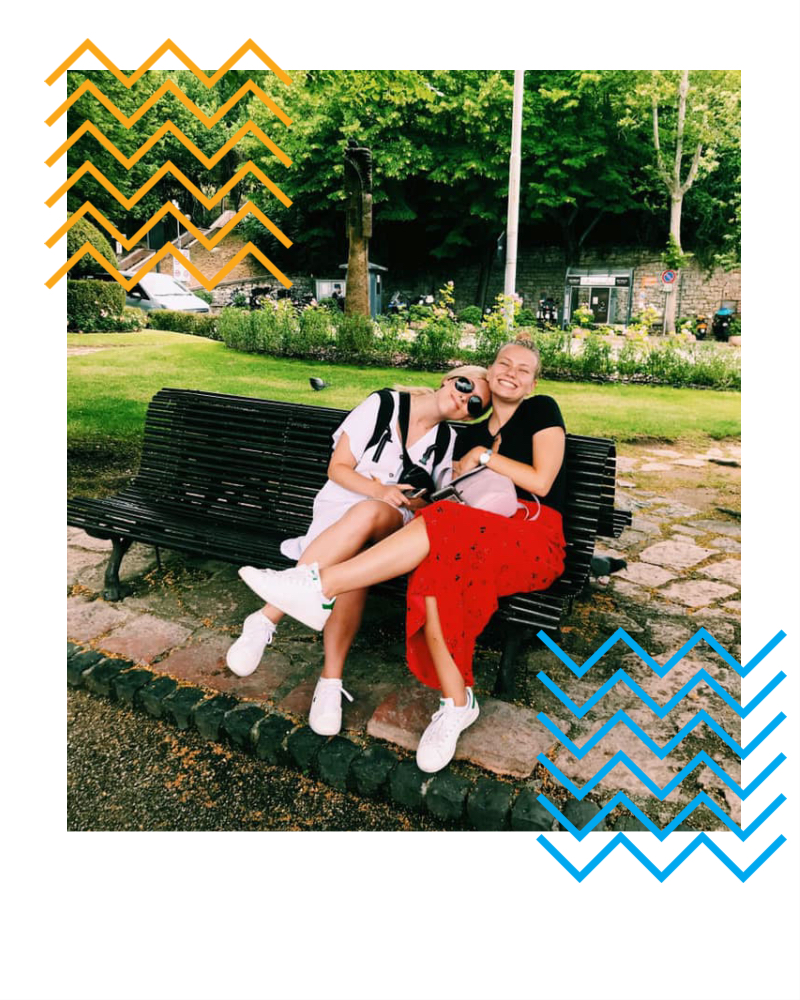 Kristin with a friend sitting on a bench in a city in Europe