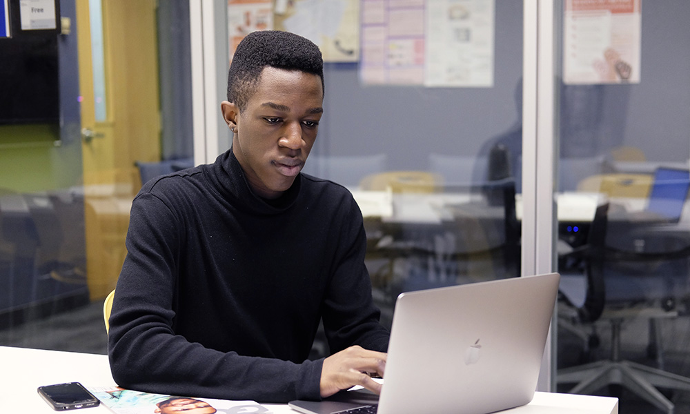 A student working on a laptop in a school study space.