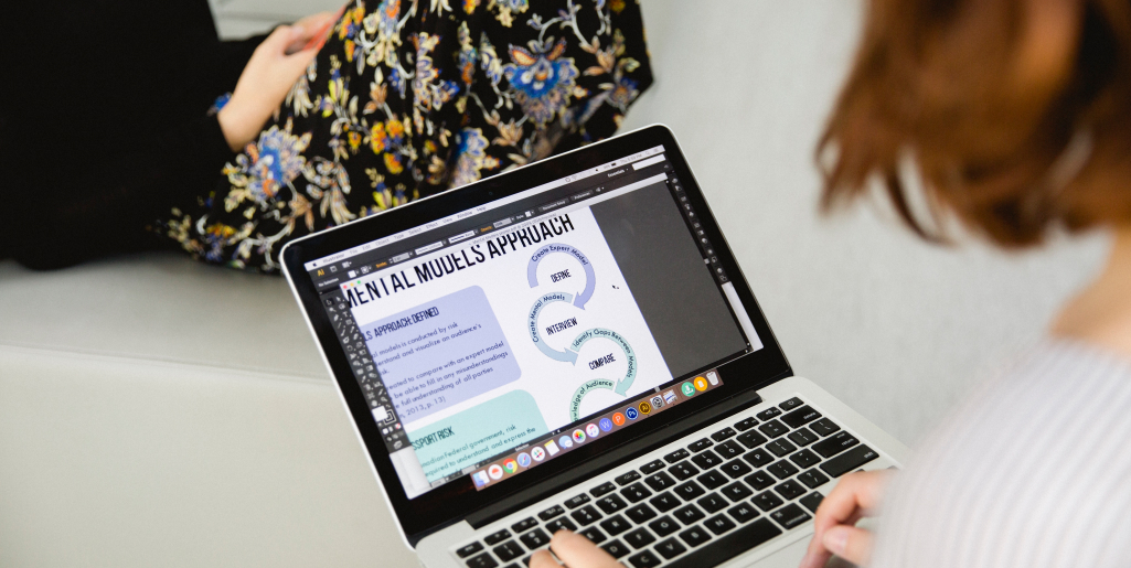 A close-up of a person using a laptop with a graphic design open on the screen.