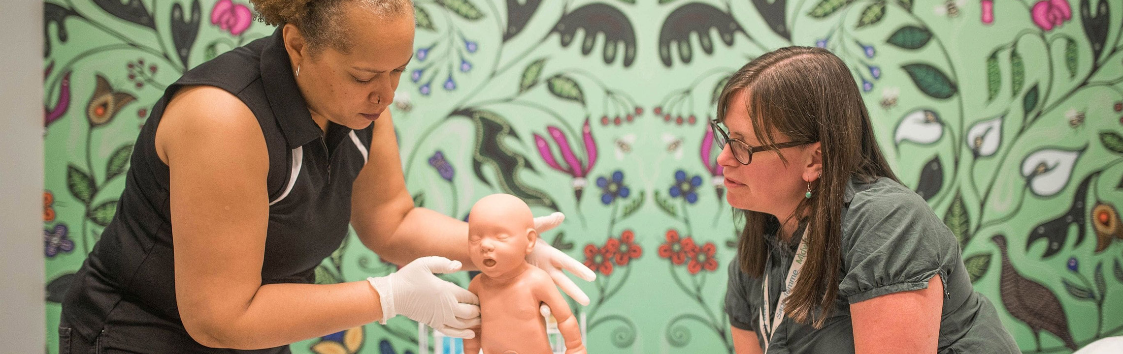 A midwife using a training model to demonstrates how to hold an infant.