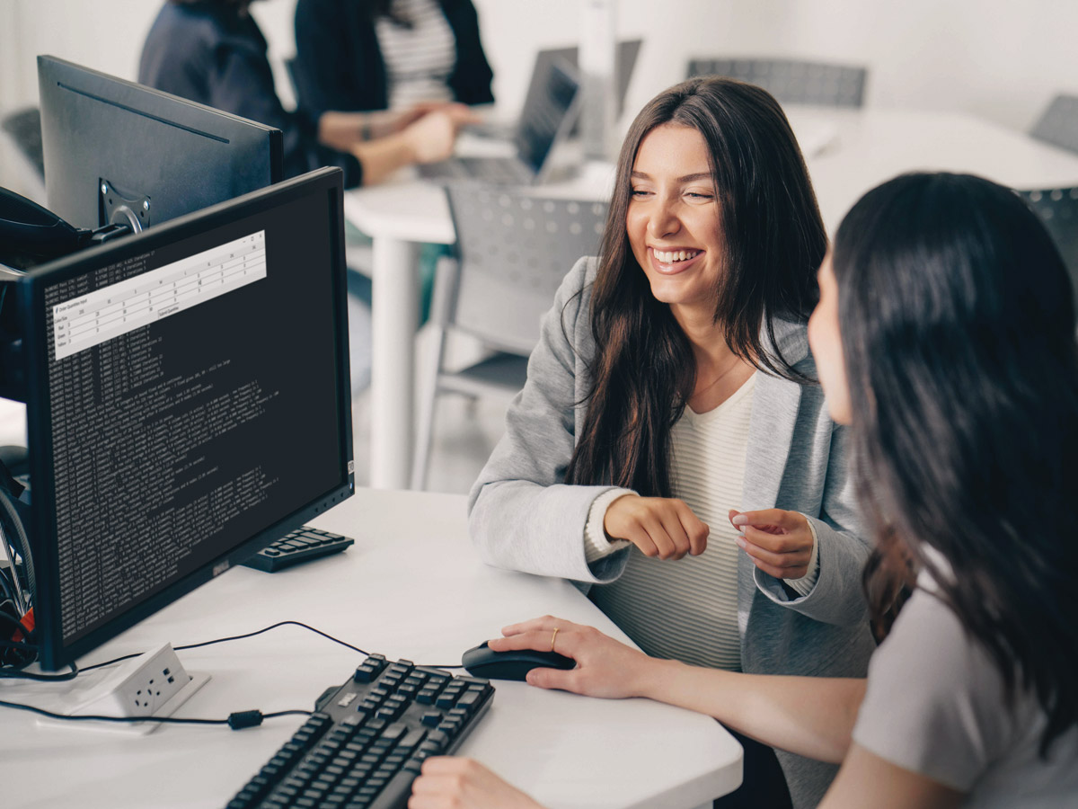 A pair of Industrial Engineering students laugh while working together in a computer lab.