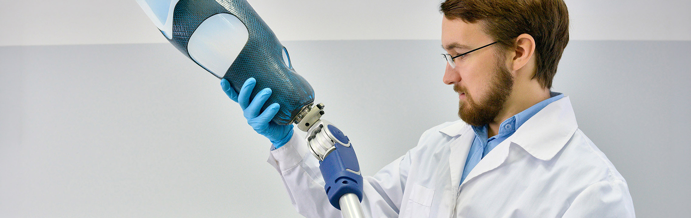 A Biomedical Engineering student in a lab coat inspects a prosthetic leg.
