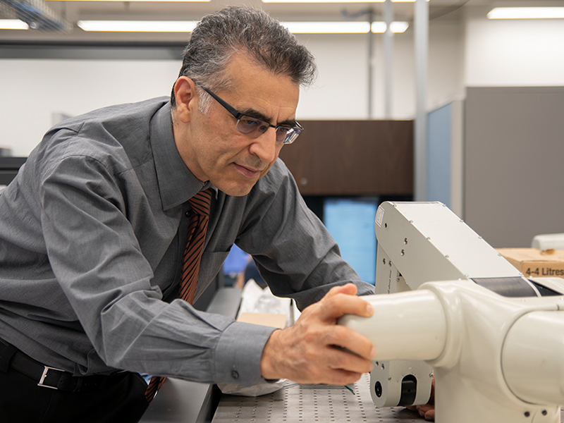 Dr. Farrokh Janabi-Sharifi inspecting and looking at a robot arm. 