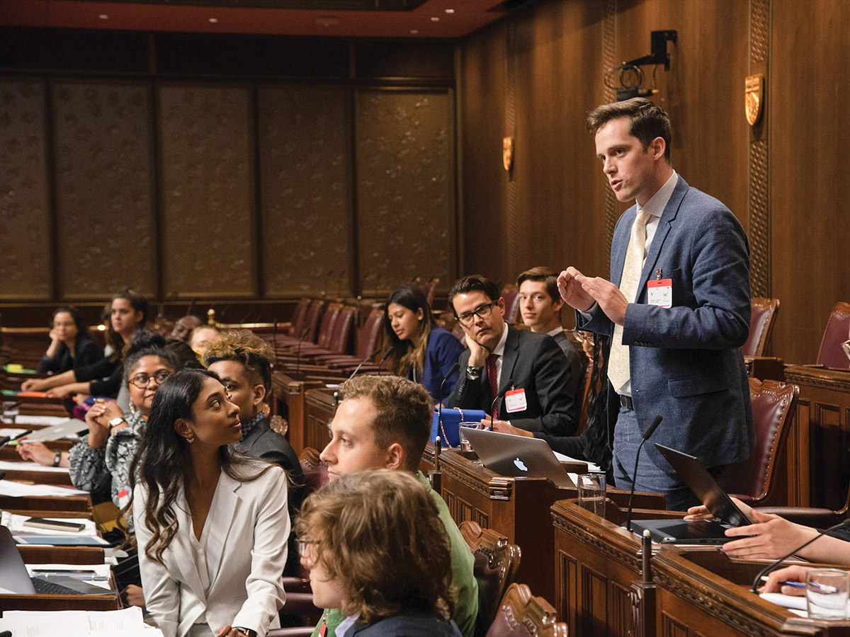 Matthew Chisholm, acting as the minister of health, addresses other IFL participants, who serve as members of parliament. 