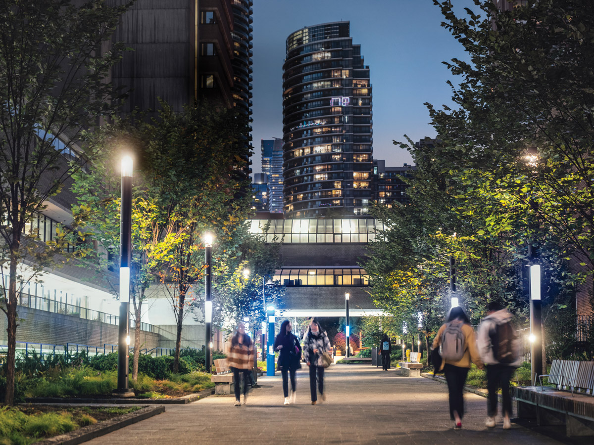 Students walk by the buildings and trees around the brightly lit Nelson Mandela Walk on campus.
