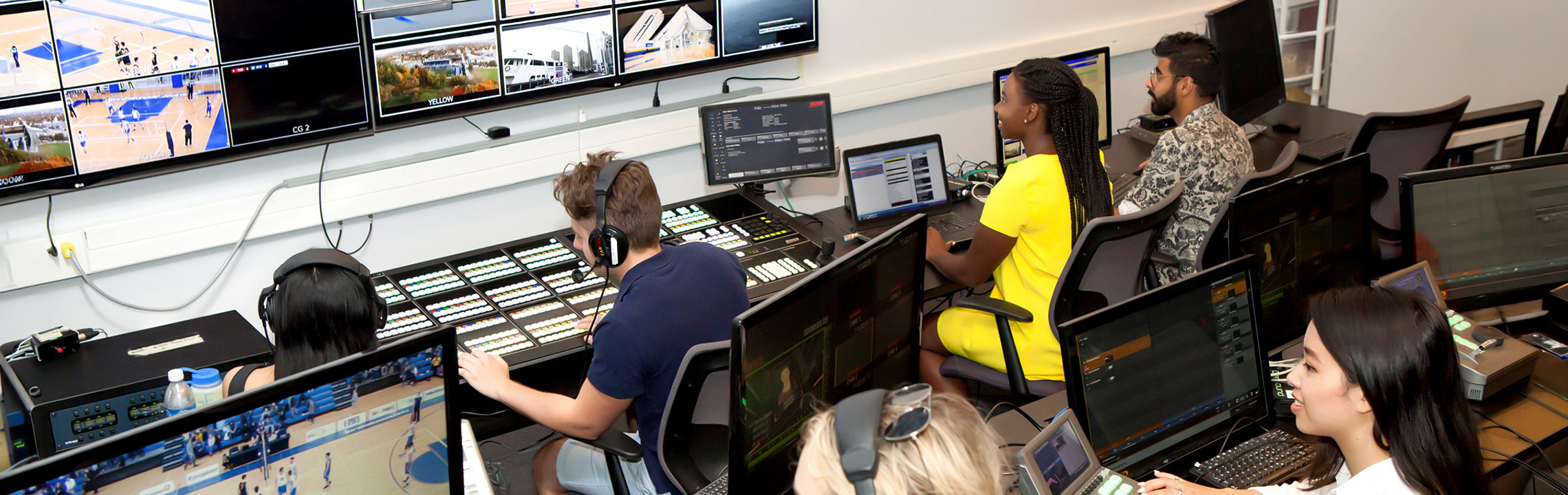 Sport Media students working on computers and soundboards in a lab on campus.