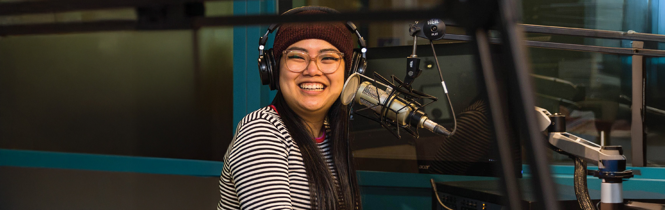 A student laughs while recording audio at the Allan Slaight Radio Institute.
