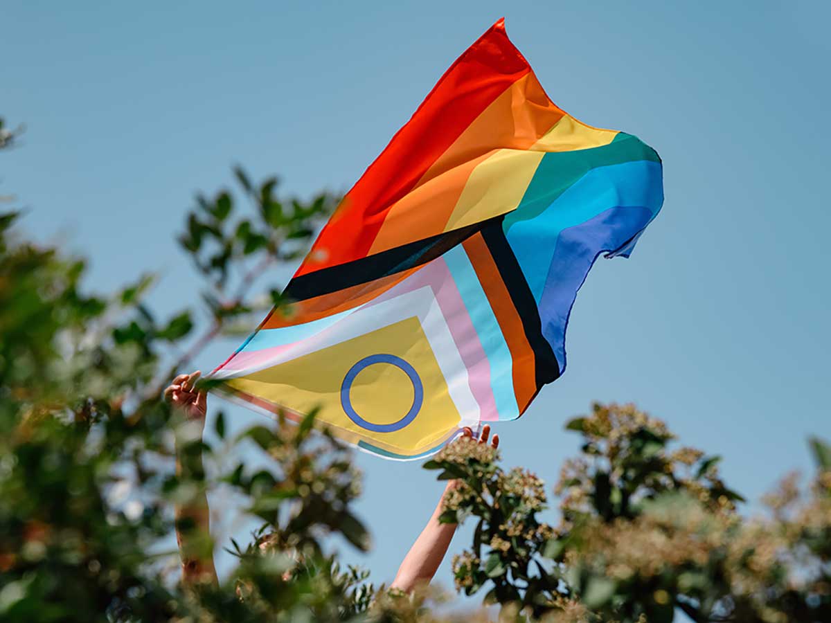 A TMU student celebrates and waves Intersex-Inclusive Progress Pride flag in the air