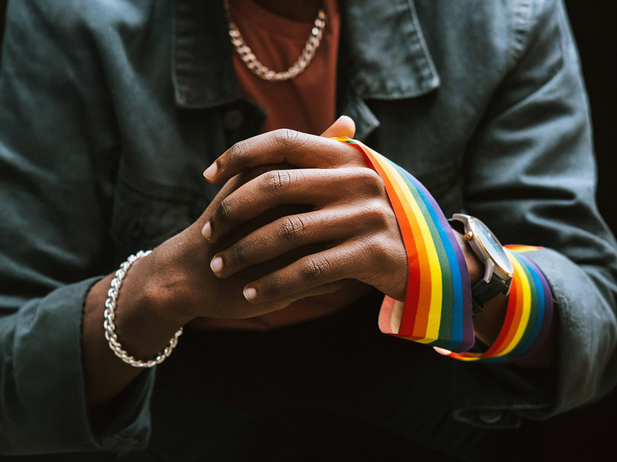 Close-up of TMU student's hands with a Pride ribbon wrapped around left hand