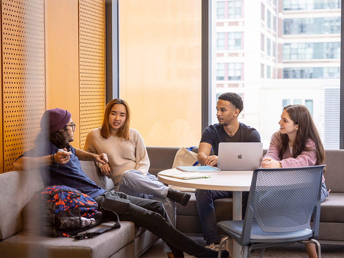 TMU students sitting around a lounge table socializing.
