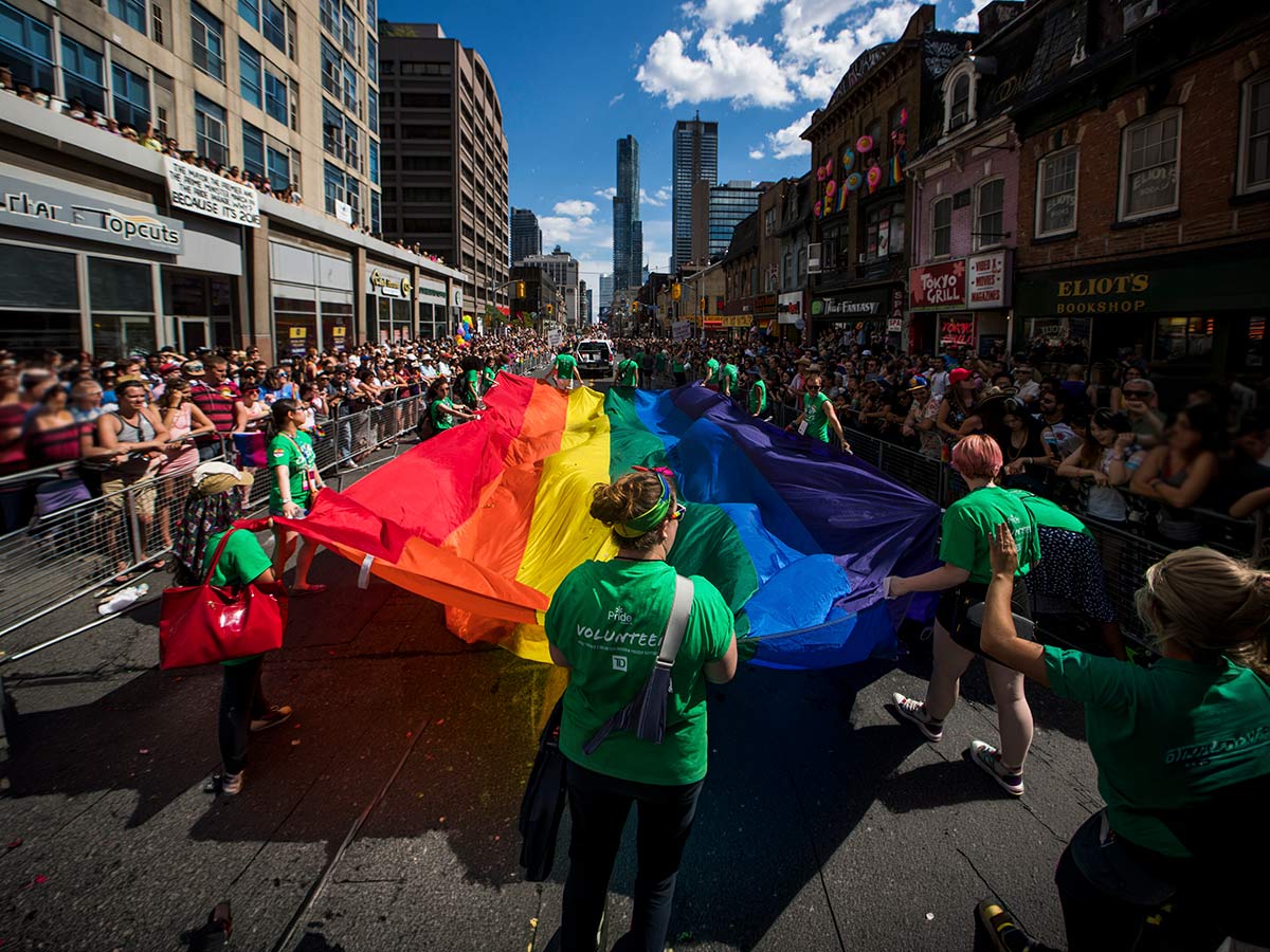 TMU students celebrate waving a large Pride flag at the Pride Parade in Toronto