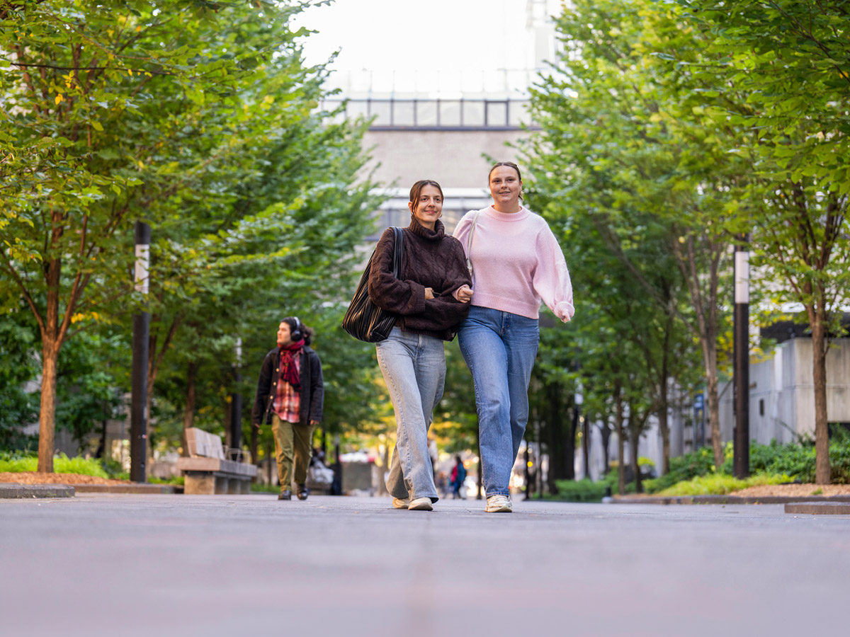 Students walking on campus linking arms and smiling