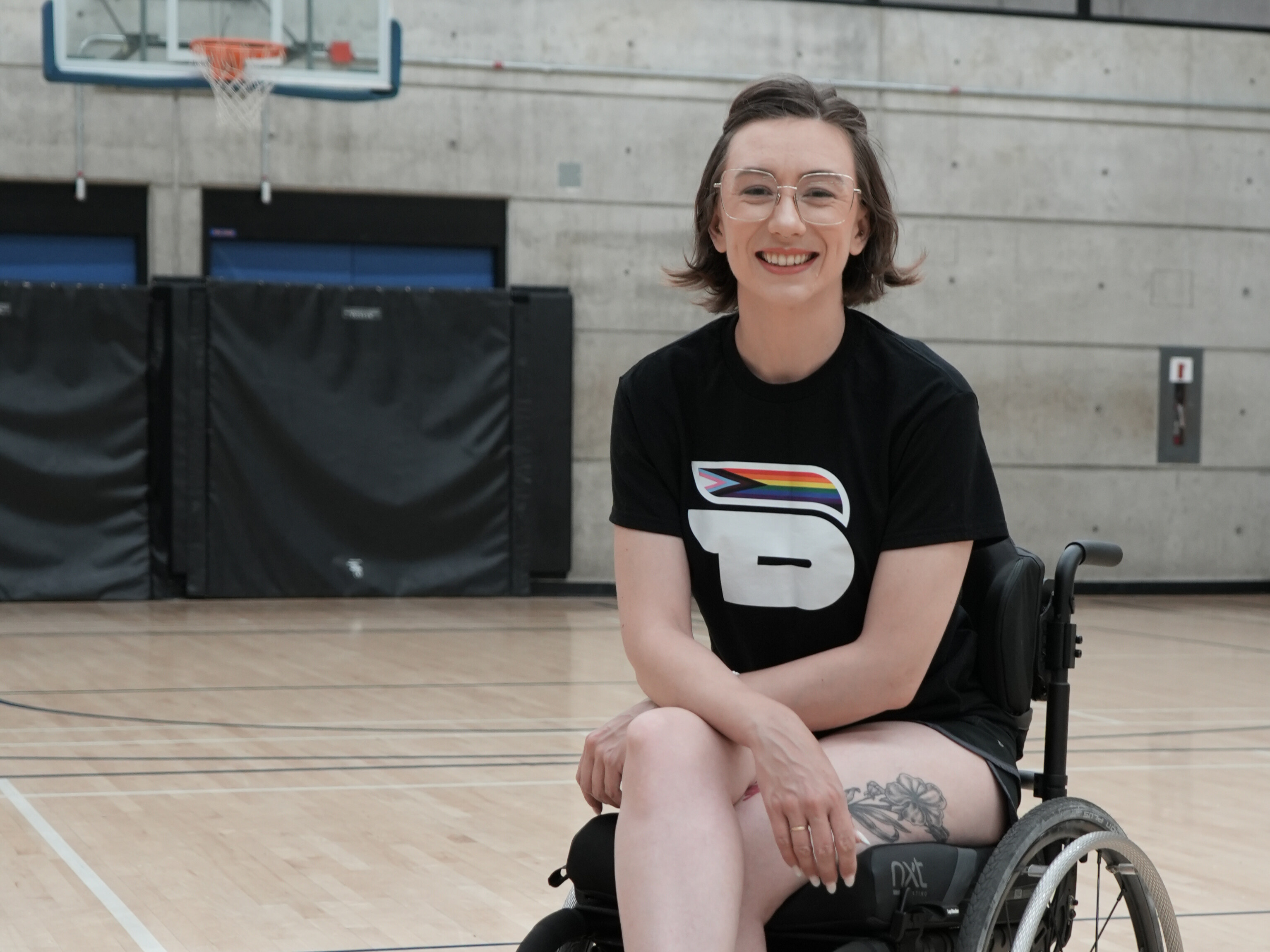 Wheelchair user poses in basketball gym