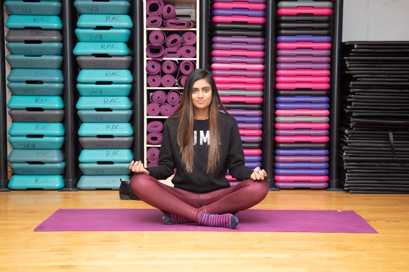 Christina Paruag sits on a Yoga mat with legs crossed