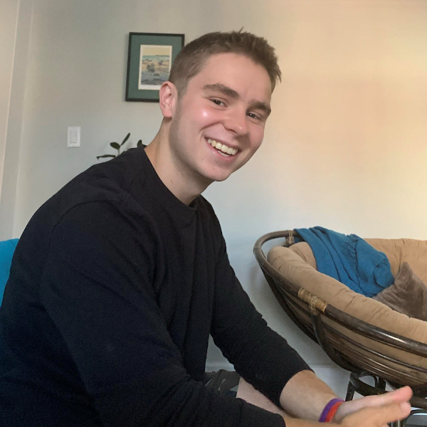 Max Loslo poses for a photo while sitting in a living room.