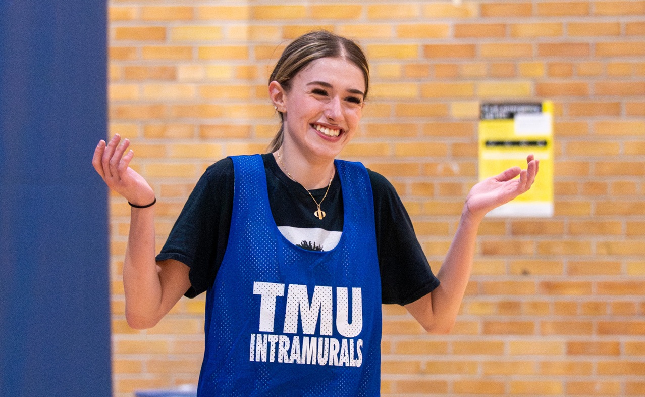 An intramural basketball player shrugs her shoulders and smiles