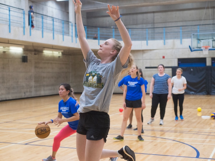 A line of girls taking shots at the basketball hoop.