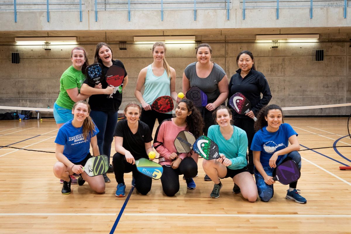 A group of ten women pickleball players pose for a photo in the RAC
