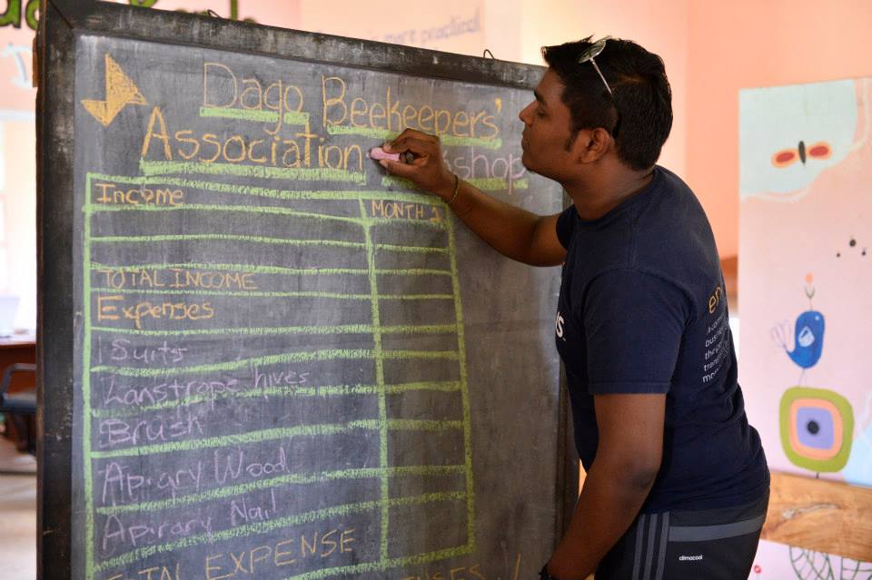 A Dago Beekeepers Association member writing on a blackboard about expenses and income of the association
