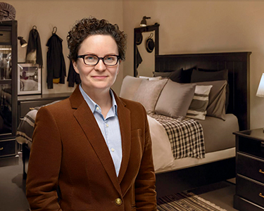 Psychology Researcher, Colleen Carney, sits in a tidy bedroom. 