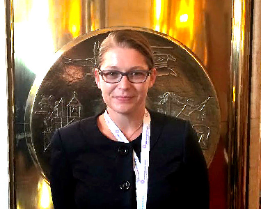 Nursing Researcher, Kristine Newman, stands in front of an ornate, circular metal plaque.