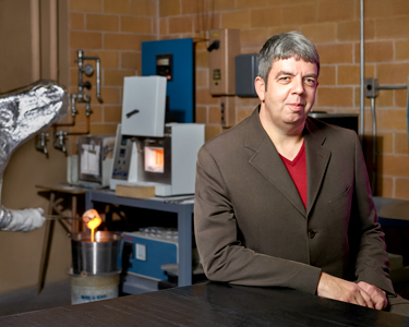 Mechanical and Industrial Engineering Researcher, Mark Towler, sits at a desk in a mechanical room.