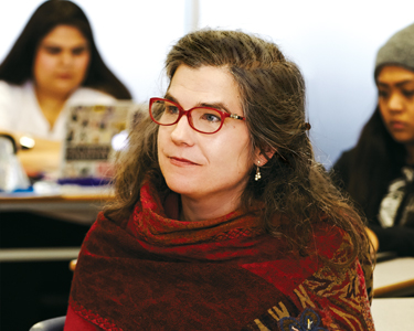 Child and Youth Care Researcher, Tara Collins, sits attentively in a classroom. 