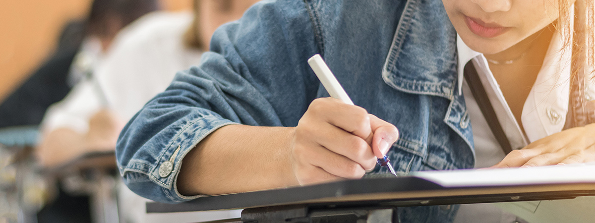 School student's taking exam, thinking hard, writing answer in classroom for educational university admission test and world literacy day concept