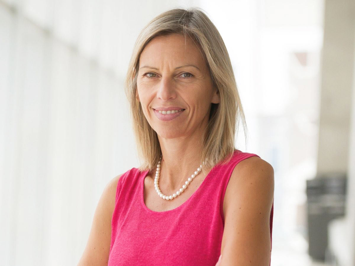 Professor Anna Triandafyllidou, wearing a pink sleeveless top and a pearl necklace.