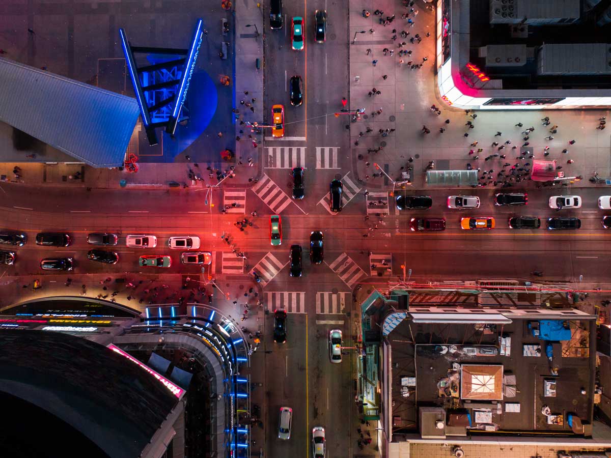 A aerial view of vehicle and pedestrian traffic at the intersection at Yonge and Dundas streets in Toronto at night.