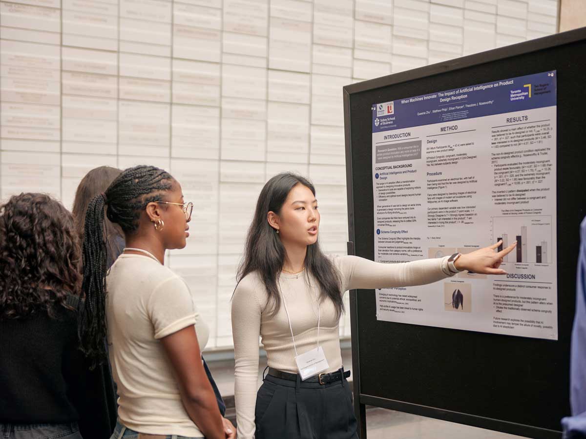 An undergraduate student points out a bar graph showing survey results on her poster to a showcase attendee.
