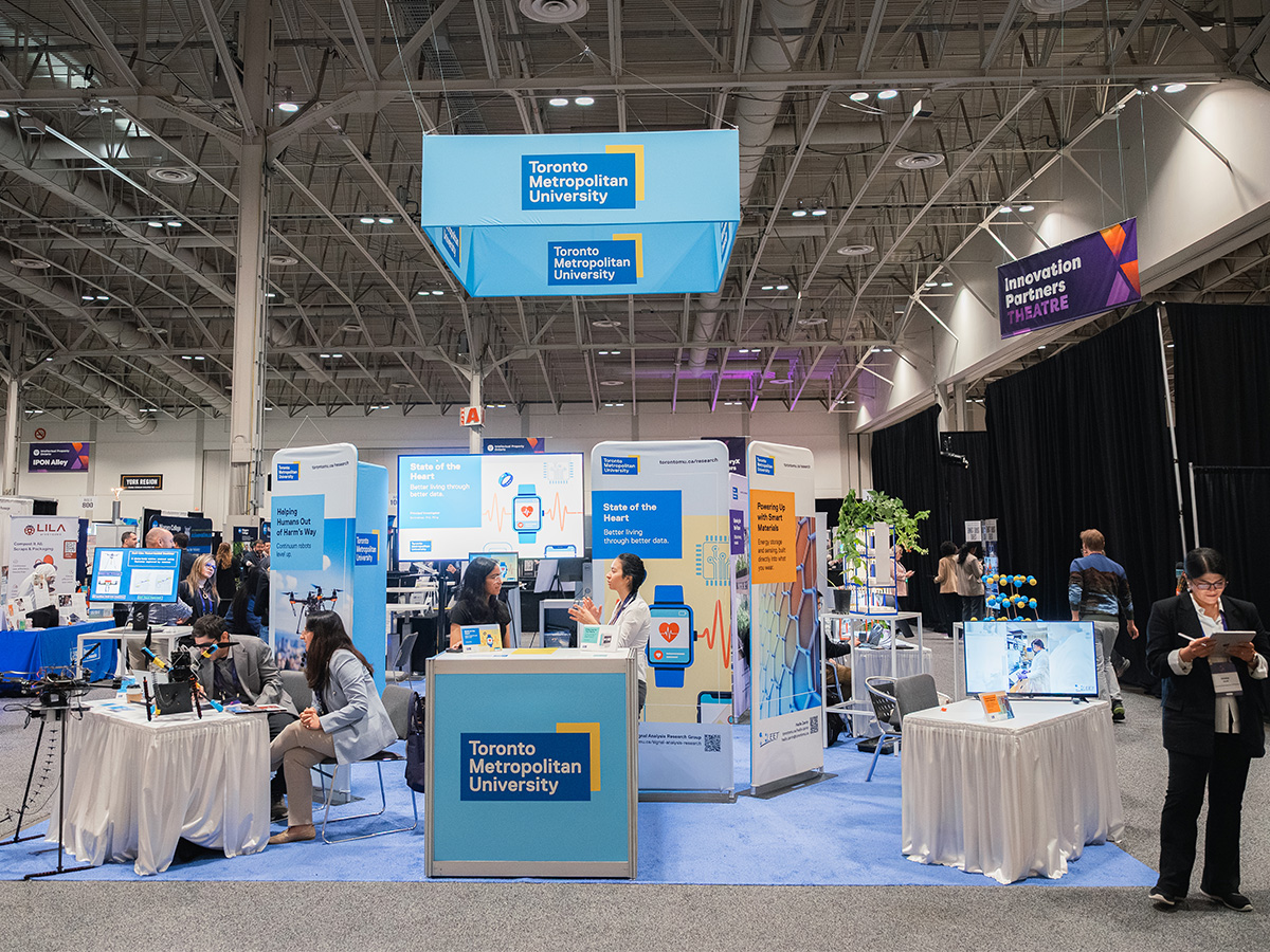 Toronto Metropolitan University’s booth at the DiscoveryX conference features interactive displays on health technology, robotics and sustainable innovation, with researchers speaking to attendees inside a large exhibition hall