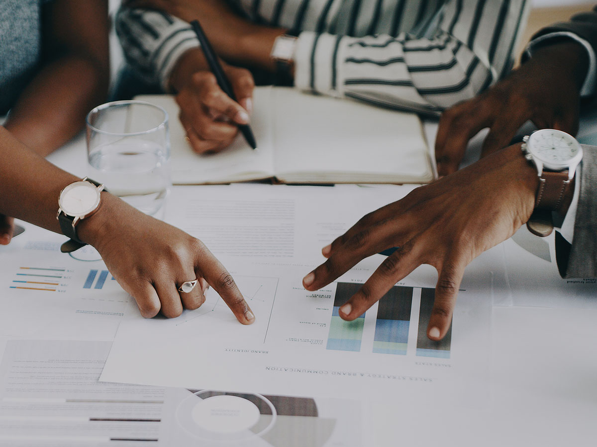 A group of young people analyze graphs around a conference table