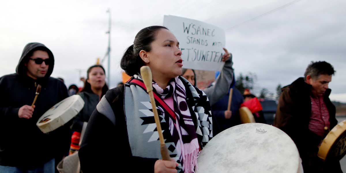 An indigenous woman at a protest holds a drum.