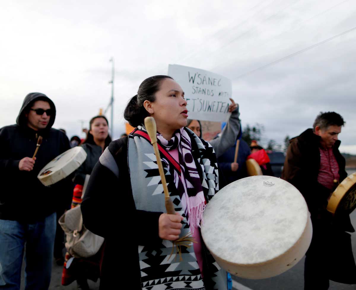 An Indigenous woman at a protest holds a drum.