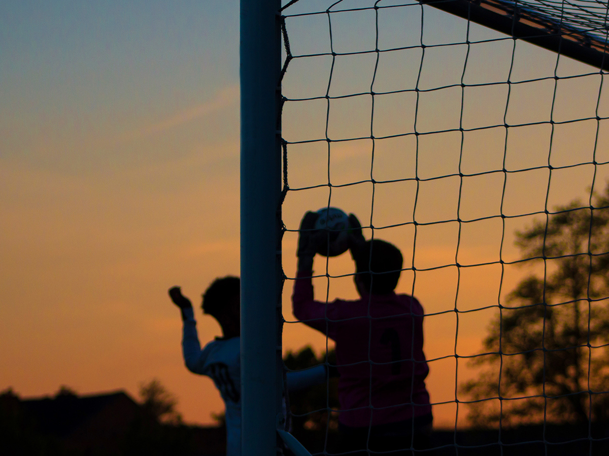 Children playing soccer at dusk