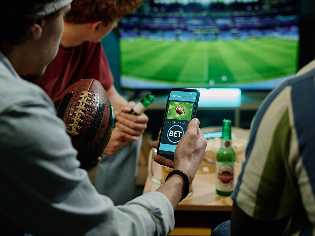 A group of friends watch a sporting event on TV while drinking beers.