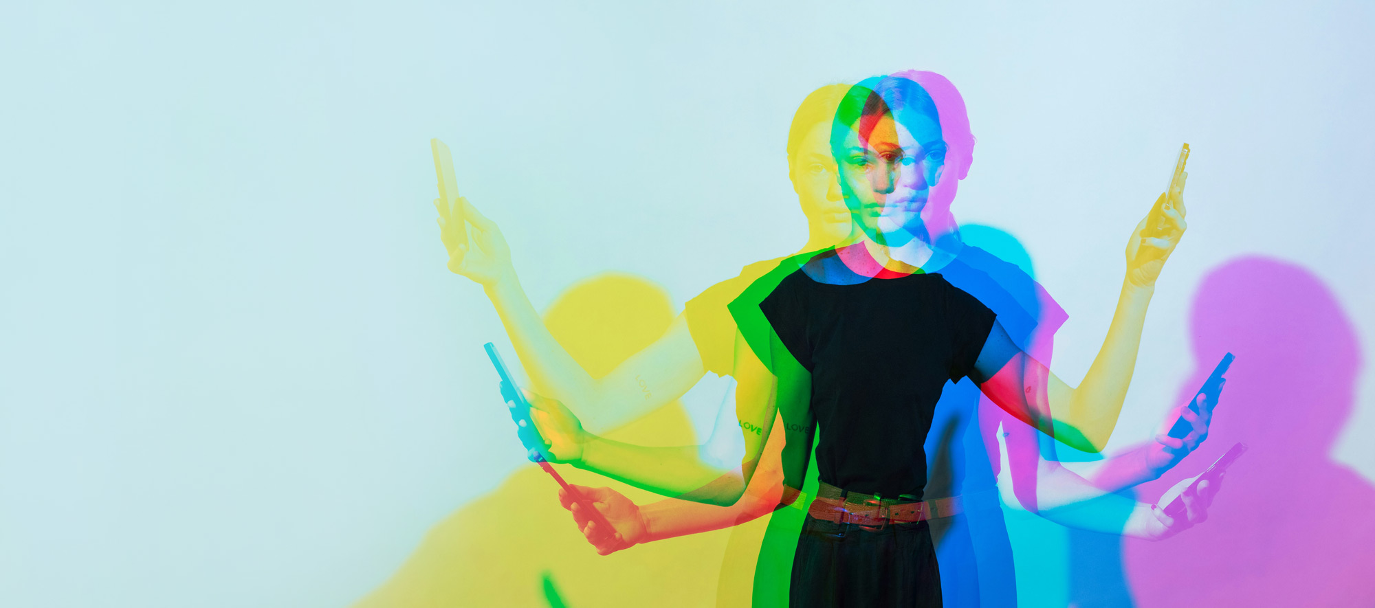 Multiple exposures of a young woman with a cell phone in each hand. Her shadow is depicted in different colours.