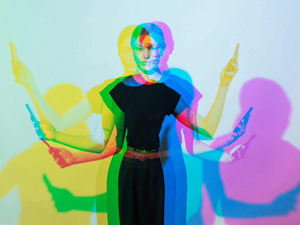 Multiple exposures of a young woman with a cell phone in each hand. Her shadow is depicted in different colours.